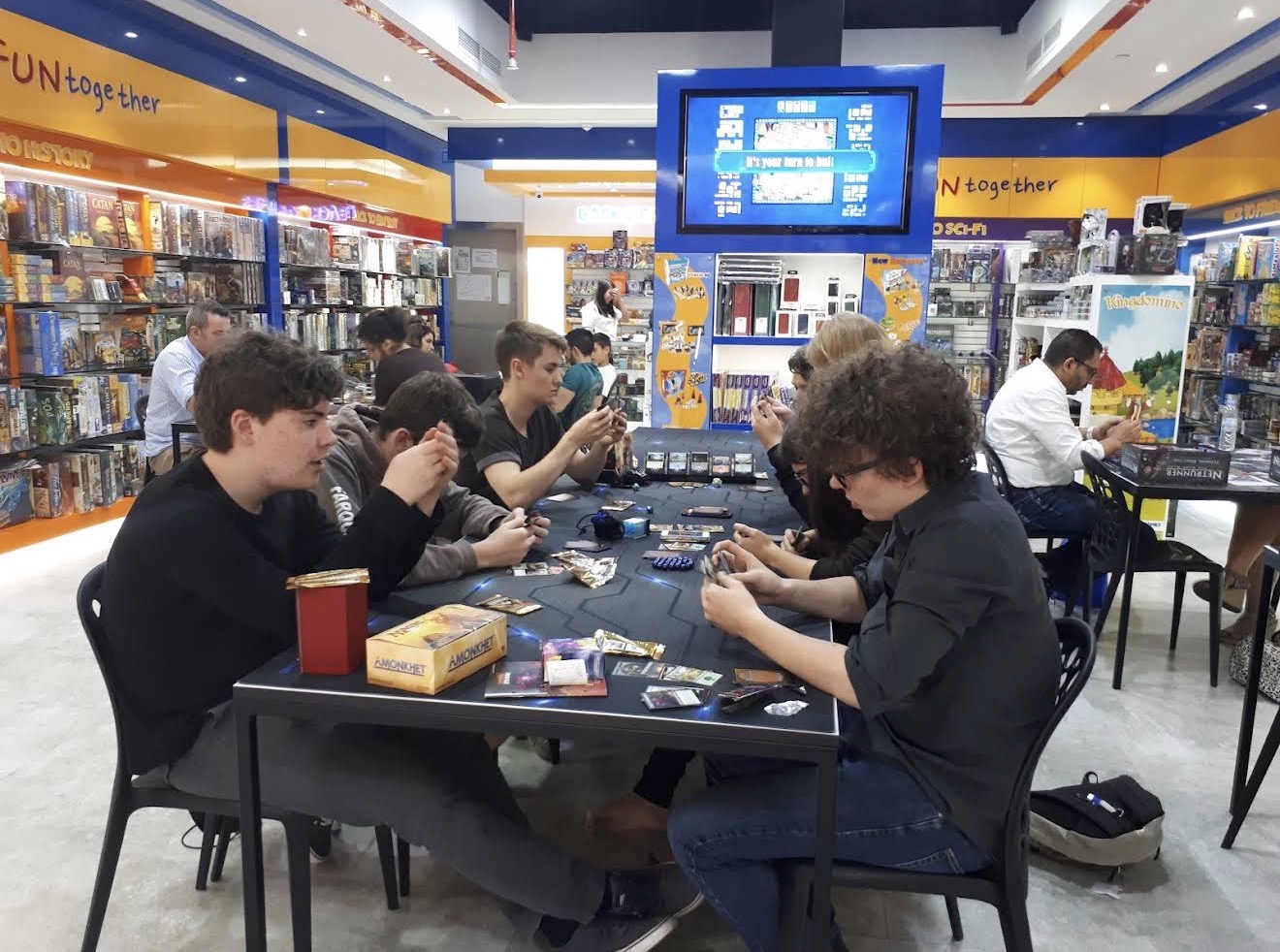 Players gathering around a game table at Back to Games Times Square Center